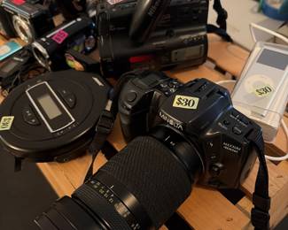 1. Apple iPod Nano (1st Generation) 2. Unisonic XL-985 Portable TV/Radio/Cassette Recorder & Quartz Clock 3. Bose PM-1 Portable CD Player 4. Petri FT 35mm SLR Camera 5. Minolta Maxxum 400si 35mm SLR Film Camera 6. Fujifilm FinePix E900 Digital Camera 7. Generic 3.1 MP Digital Video Camcorder 8. Nikon Action-8 VN-310 8mm Video Camcorder 9. Franklin Bookman Electronic Holy Bible (KJB-440)