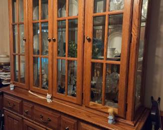 Vintage solid Oak China hutch featuring 4 glass pane doors with display lighting , glass shelving, and ample lower drawer/cabinet storage classic brass hardware & clean traditional styling. (Note contents inside not included unless purchased separately)