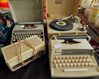 Vintage Electronics & Typewriters: Vintage Sears portable record player with hard case, General Electric (GE) solid-state table radio, and portable manual typewriters (Royal Mercury and Penneys Lite-Touch).