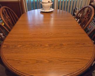 Solid Oak dining table Cochrane with beautiful wood grain featuring ornate press-back wooden chairs with extensions. Very sturdy well maintained & ready for family dinners!
