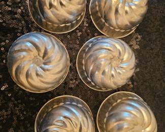 A set of six vintage aluminum miniature swirled bundt cake molds.