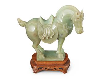3094 A Chinese carved hardstone horse 20th century Raised on a carved wood stand with metal inlay Height of stone 6 1/4 in., width 7 in., depth 3 3/4 in.; height of stand 1 3/8 in., width 4 1/2 in., depth 3 in. Estimate: $200 - $400