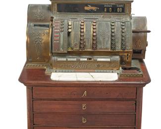 3058 A National Cash Register and oak cash drawers Early 20th century Comprising a gilt-brass-cased cash register with columns of multi-denomination keys, raised on a small wood chest of four drawers, labeled 'A,' 'B,' 'D,' and 'E' Height combined 33 in., width 30 1/4 in., depth 31 1/4 in.; height of register 17 1/4 in. Estimate: $400 - $600