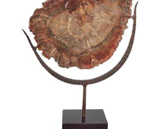 3327 A petrified wood cross section specimen Late 20th/early 21st century Mounted in a stylized patinated metal stand with stone base Height of specimen 11 3/8 in., width 15 3/8 in.; depth 1 in.; height of stand with base 21 in., width 16 in., depth 6 1/4 in.; height overall 24 1/2 in. Estimate: $300 - $500