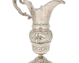 3420 A Continental silver plated ewer 20th century The silver-plated hammered metal footed ewer with repoussé floral medallions and geometric motifs to body, with an ornately formed scrolled handle Unmarked Height 14 1/2 in., width 9 3/4 in., depth 5 1/2 in. Estimate: $100 - $200