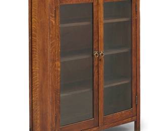 3049 An Art & Crafts style oak bookcase Late 20th century The quarter-sawn oak cabinet with iron pulls to glazed doors, opening to reveal three adjustable shelves Appears unmarked Height 51 1/2 in., width 32 1/4 in., depth 12 3/4 in. Estimate: $700 - $900