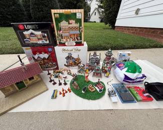 Village Accessory set - includes all items shown in picture. Lowes porcelain building, Lemax Ski lodge, Lemax Samuels hardware, Harborside village fish market. LGB passenger waiting room, lighthouse, train station, fire station, 2 small houses, 2 gas pumps, and assorted people/animals, bag of snow, and lights. Price - $38.00