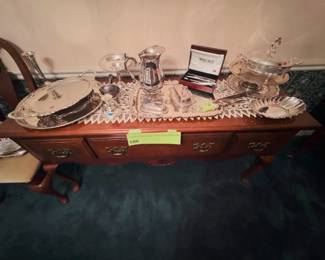 American Drew Queen Anne 5-Foot sideboard with silver-plate water pitcher, trays, butter dishes, candlestick, bud vase, compote, covered casserole, shell bowl, and boxed Wallace Silversmiths set.