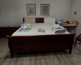 dark wood sleigh bed with blue-and-white bedding, matching nightstands, and framed artwork