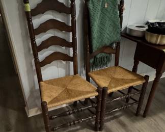 dark wood ladderback chairs with woven rush seats, with one chair draped with a green throw blanket