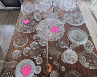 clear pressed glass: EAPG cake plate, Indiana Glass Tiara Sandwich Daisy & Scroll salad/dessert plates, heart-shaped dish, pedestal cake stand, frosted floral platter, cranberry-edged bowl, candleholders, creamers, relish dishes, and salt and pepper shakers