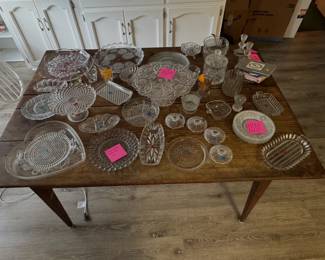 clear glass tableware, including cake stands, serving trays, a heart-shaped platter, bowls, and glassware; THE TABLE IS NOT FOR SALE.