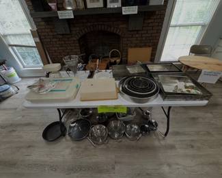 kitchen items and cookware, including baking pans, cake tins, a food mill, a scale, and stainless steel pots and pans
