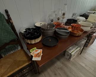 assortment of baking pans, Bundt pans, copper tone molds, and glass oil lamps