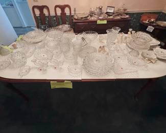 Fostoria American bowls, platters, pitchers, vases, candleholders, relish dishes, and salt and pepper shakers, on an American Drew Queen Anne extension dining table with 8 matching chairs (6 side chairs and 2 armchairs)