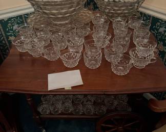 wooden serving cart displaying large Fostoria American punch bowls and numerous matching punch cups