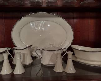 Lenox Solitaire fine china serving pieces, including an oval platter, gravy boat, sugar bowl, creamer, and salt and pepper shakers displayed inside a wooden china cabinet
