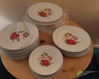 Mikasa Italian Holiday porcelain dinnerware featuring poinsettia motifs, holiday horns, and a matching cake server arranged on a wooden table