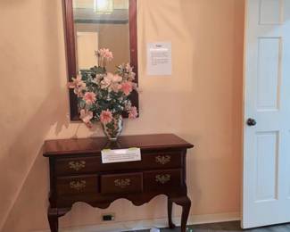 traditional Queen Anne-style dark cherry wood server with brass batwing drawer pulls and cabriole legs, and a traditional Queen Anne-style dark cherry wood mirror with a broken-arch pediment and topped with a central finial