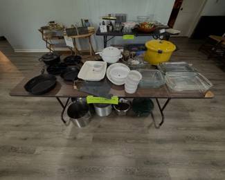 cast iron skillets, glass baking dishes, white ceramic serving pieces, a large yellow pressure cooker, and additional cookware