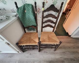 pair of ladder-back chairs with rush seats and turned stretchers; green fringed throw