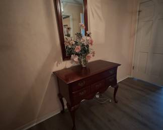 traditional Queen Anne-style dark cherry wood server featuring brass batwing drawer pulls and cabriole legs, paired with a tall matching wall mirror with a broken-arch pediment and a central finiall
