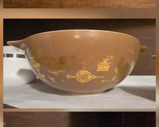 Pyrex Early American, featuring gold-toned graphics of an eagle, rooster, and colonial-style motifs like a stove and spinning wheel.
