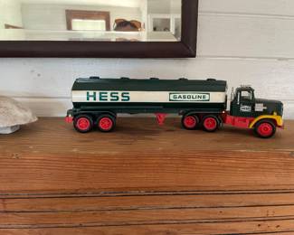 1984 A plastic toy truck and tanker trailer combination painted in dark green, white, and red with yellow fenders. The side of the cylindrical tank bears the bold green lettering HESS and GASOLINE.