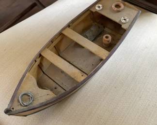 Wooden Rowboat Model A handcrafted wooden rowboat model featuring visible planking, built-in wooden bench seats, and miniature nautical accessories including coiled rope and buoys. The interior showcases natural wood tones with dark trim along the gunwales.