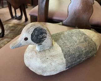 1920-40 Duck Decoy A hand-carved wooden duck decoy featuring a solid body and distinct painted markings, including a dark patch on the head and a grey back over a white-painted breast. The simple bill and painted eye details reflect traditional folk art craftsmanship.