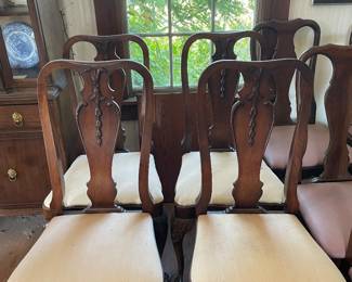 A set of traditional wooden dining side chairs featuring carved splat backs with classical shell or floral motifs, cabriole legs, and upholstered drop-in seat cushions in a neutral fabric.