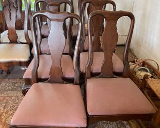 These are traditional wooden dining chairs featuring a classic Queen Anne style with vase-shaped splat backs, gently curved stiles, and cabriole legs terminating in pad feet. The upholstered drop-in seats are covered in a faded mauve fabric.