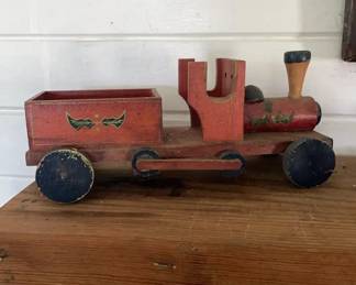 Vintage Wooden Locomotive Toy 1930-1950 This is a handcrafted wooden toy train locomotive painted red with blue wheels and decorative leaf motifs along the body and tender. It features a prominent wooden smokestack and an open cab structure.