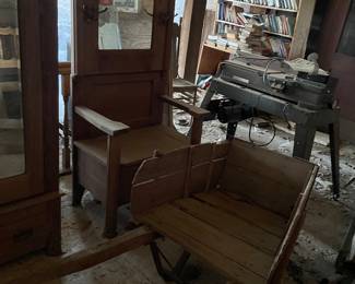 Oak Hall Tree 1890-1915 A tall wooden hall tree featuring an integrated bench with a lift-up storage seat, an upright back panel holding a central beveled mirror, and several cast iron coat hooks mounted to the frame.