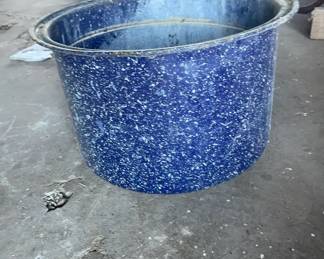 Graniteware Canning Pot 1900-1940 This is a large cylindrical metal pot featuring a dark blue enamel body with white speckled patterns throughout. It has a flared rolled rim and shows heavy signs of outdoor use and storage.