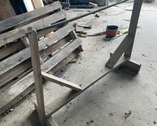 Tobacco Sawhorse 1900-1920 This is a primitive wooden sawhorse constructed from rough-hewn planks and a long central pole, designed specifically for agricultural handling. It features upright posts reinforced by diagonal wooden braces resting on simple rectangular footings.
