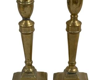 2091 - Pair Brass Candleholders 10.5" (Description): A set of two brass candleholders featuring  elegant urn-shaped cups atop tapered stems  with decorative banding. Each candleholder  rests on a stepped square base. Measures 10.5  inches tall.