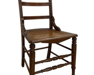 7669 - Antique Ladder Back Cane Seat Chair (Description): Antique ladder back side chair featuring a  woven cane seat. The chair displays elegant  turned front legs and decorative turned  stretchers. The back consists of three  horizontal slats with graceful curved stiles. The wood has a warm brown finish with a  nicely aged patina. Measures 34 inches in  height by 16 inches in width by 17 inches in  depth.