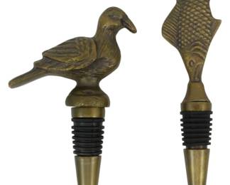 160 - 2 Brass Figural Wine Bottle Stoppers (Description): 2 Metal wine bottle stoppers featuring brass  figural designs. One stopper is topped with a  detailed bird figure, while the other  features a stylized fish design. Both  stoppers have conical brass points with rubber gasket rings for a secure seal in wine  bottles. Attractive barware accessories with  an antiqued brass finish.