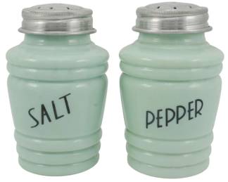 150 - Jadeite Salt and Pepper Shakers 5" (Description): Pair of jadeite glass salt and pepper shakers  measuring 5 inches tall. The shakers feature  a ribbed barrel design in the classic pale  green jadeite color, with "SALT" and "PEPPER"  printed in black lettering on the front. Each shaker is fitted with a screw-top lid  with perforated holes.