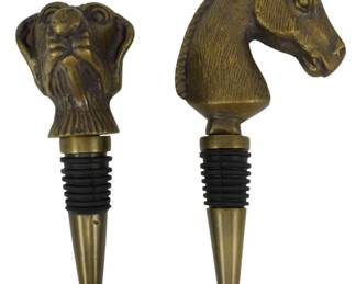 161 - 2 Brass Animal Head Wine Bottle Stoppers (Description): 2 Metal animal wine corks featuring  decorative figural heads. One stopper is  topped with a detailed dog head, while the  other features an elegant horse head. Both  have an antique brass finish and are fitted with rubber gasket rings for a secure seal in  wine bottles. The stoppers have tapered  brass points below the rubber seals.