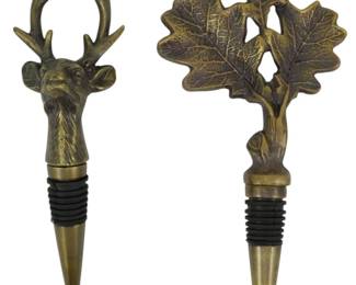 159 - 2 Brass Figural Wine Bottle Stoppers (Description): Two metal wine bottle stoppers with an  antiqued brass finish. One features a  detailed stag head with antlers, while the  other displays a cluster of oak leaves with  an acorn. Both have rubber gasket seals and tapered brass ends for a secure fit in wine  bottles.