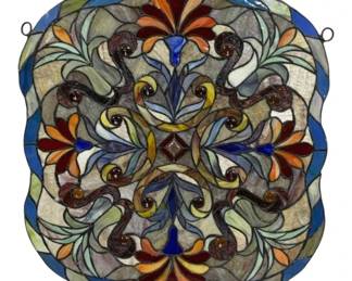 2087 - Stained Glass Wall Hanging 24"x19" (Description): Stained glass wall hanging featuring an  ornate symmetrical design with scrollwork and  floral motifs. The piece showcases a variety  of colors including blue, orange, red,  yellow, and amber glass pieces with decorative glass jewel accents. Includes  hanging rings for display. Measures 24 inches  by 19 inches.