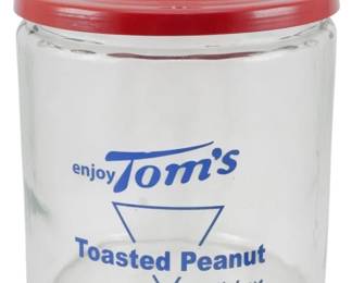 108 - Tom's Peanuts Glass Jar w/ Red Lid 10"x8" (Description): Tom's Toasted Peanuts glass counter jar with  original red metal lid featuring a knob  handle. The clear glass jar displays blue  printed advertising text reading "enjoy  Tom's" and "Toasted Peanut Delicious" with a triangular logo design. A classic general  store or diner display piece. Measures 10  inches tall by 8 inches in diameter.
