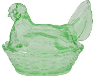 142 - Green Glass Hen on Nest Figure 5"x7"x5" (Description): Green glass hen on nest figure. This charming  covered dish features a detailed hen sitting  atop a woven basket-style nest base. The  translucent green glass has a textured  surface with molded feather details on the hen's body and wings. Measures 5"x7"x5".