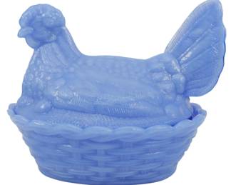 140 - Blue Glass Hen on Nest Figure 5"x7"x5" (Description): Blue glass hen on nest figure featuring a  detailed rooster lid sitting atop a woven  basket-style base. The translucent blue milk  glass showcases intricate feather detailing  on the hen and a textured basketweave pattern on the nest. Measures 5 inches by 7 inches  by 5 inches.