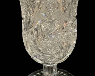 2303 - Crystal Vase 9.5", as is (Description): A crystal vase measuring 9.5 inches tall. The  piece features intricate cut glass patterns  throughout the tulip-shaped body, set upon a  footed pedestal base with chip on edge.