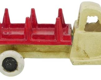 98 - Vtg Cast Iron Toy Stake Truck Yellow Red (Description): Vintage cast iron model truck featuring a  yellow cab with cut-out window details and a  red stake bed with vertical dividers. The  truck has white rubber wheels with black  centers and shows charming age-appropriate wear to the painted surfaces. Measures  2.5"x6"x2".