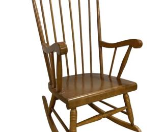 7638 - Windsor Style Spindle Back Rocking Chair (Description): Windsor style spindle back rocking chair in  warm maple finish. Features a shaped crest  rail, seven vertical spindles, curved  armrests with spindle supports, a contoured  solid wood seat, and turned stretchers connecting the rockers. Measures 41 inches  high x 24 inches wide x 23 inches deep.
