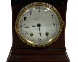 2094 - Seth Thomas Mantle Clock 10.5"x7.5"x5.25" (Description): Seth Thomas mantle clock featuring a classic  design with a wood case and brass-trimmed  dial face. The clock displays Arabic numerals  and includes winding mechanisms. Measures 10  1/2" x 7 1/2" x 5.25". Used as is electric/electronic/mechanical  item. No guarantee all components, untested.